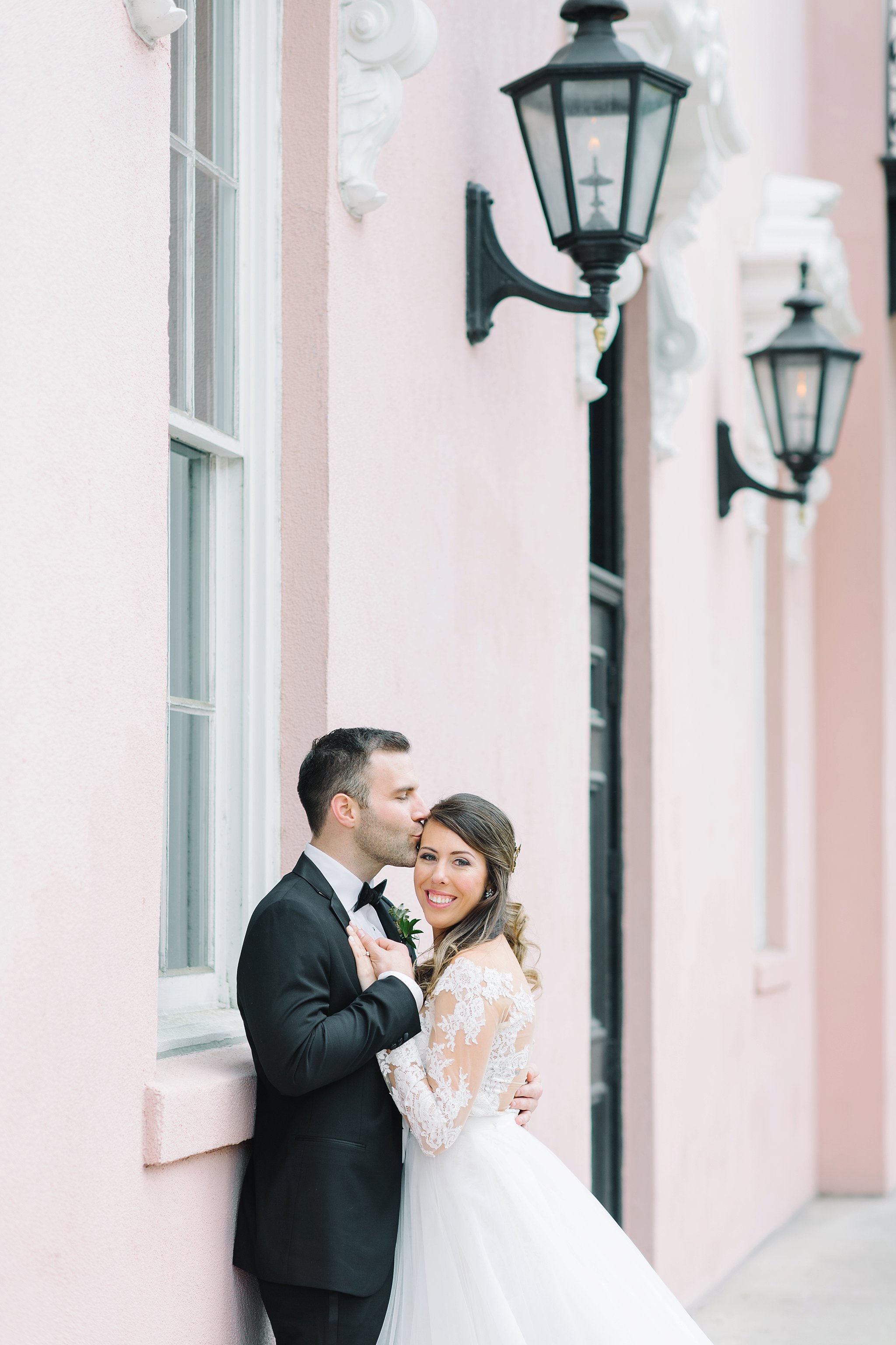 Bride and groom in front of the Mills House hotel in downtown Charleston. Black tie wedding. Wedding gown with lace sleeves