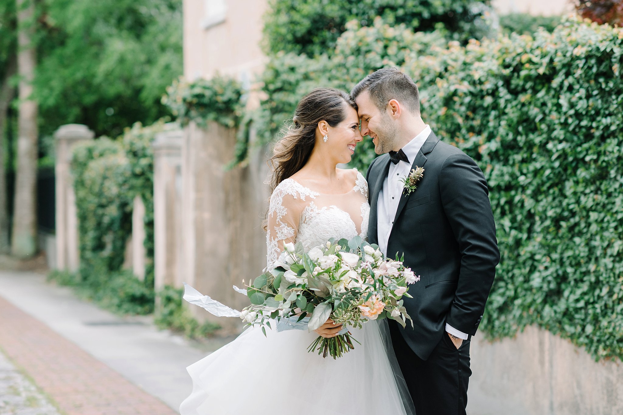 Bride and groom in downtown Charleston. Black tie wedding. Wedding gown with lace sleeves