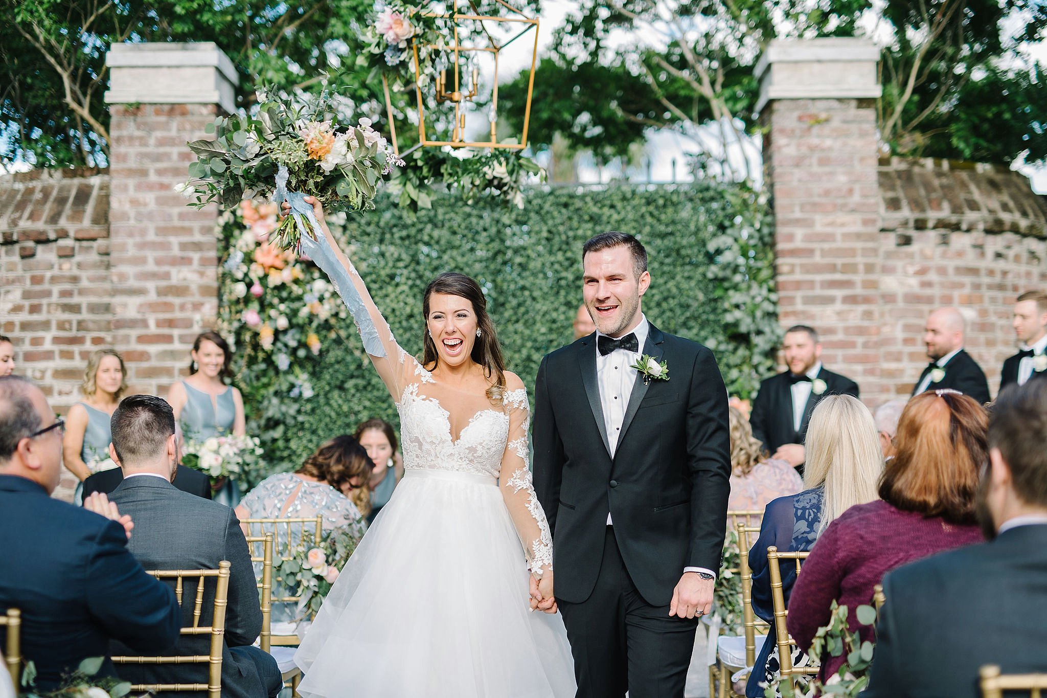 Bride and groom celebrating as they walk up the aisle at their wedding ceremony at The Gadsden House in Charleston, SC