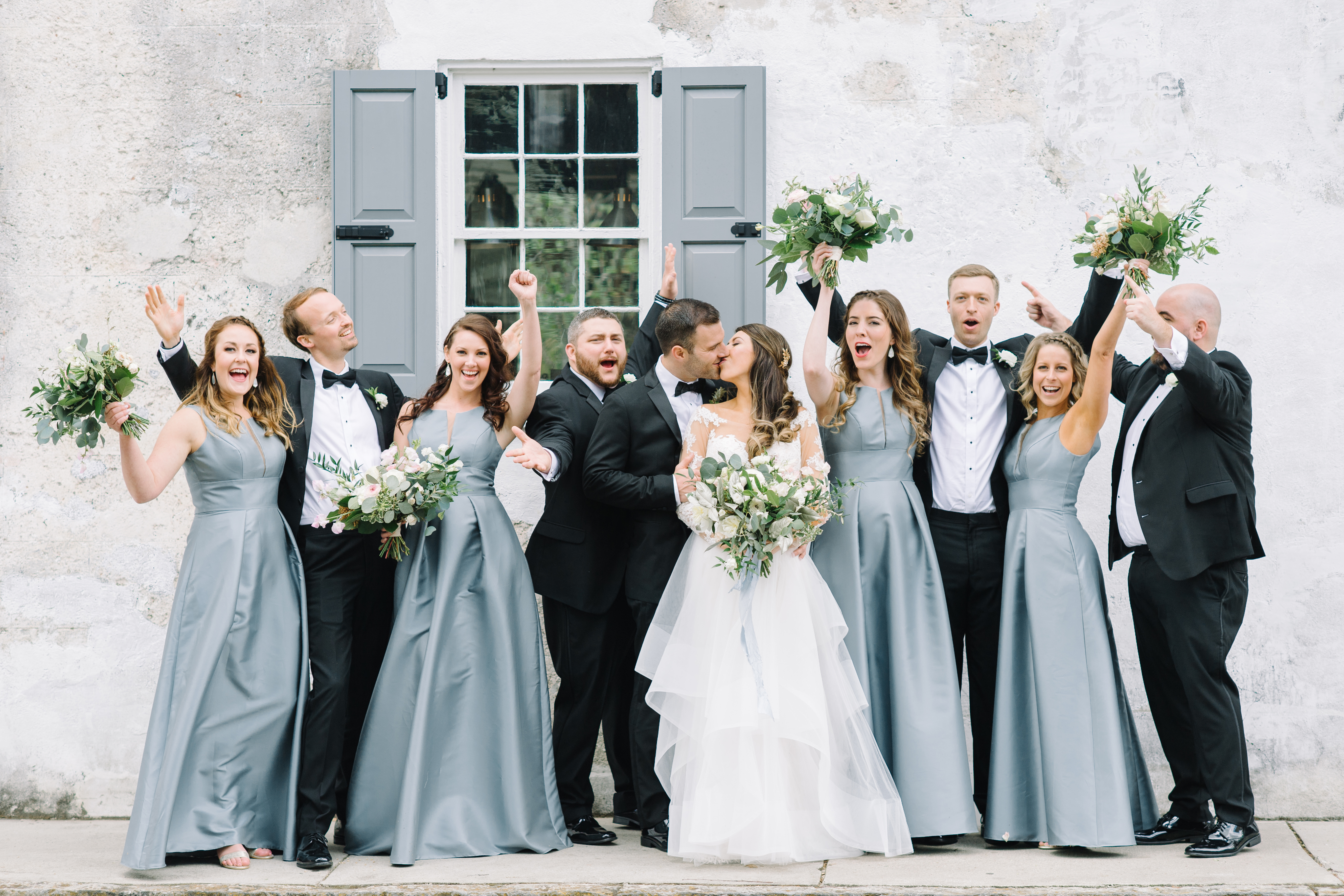 Bride and groom with their bridal party in downtown Charleston. Black tie wedding. Wedding gown with lace sleeves