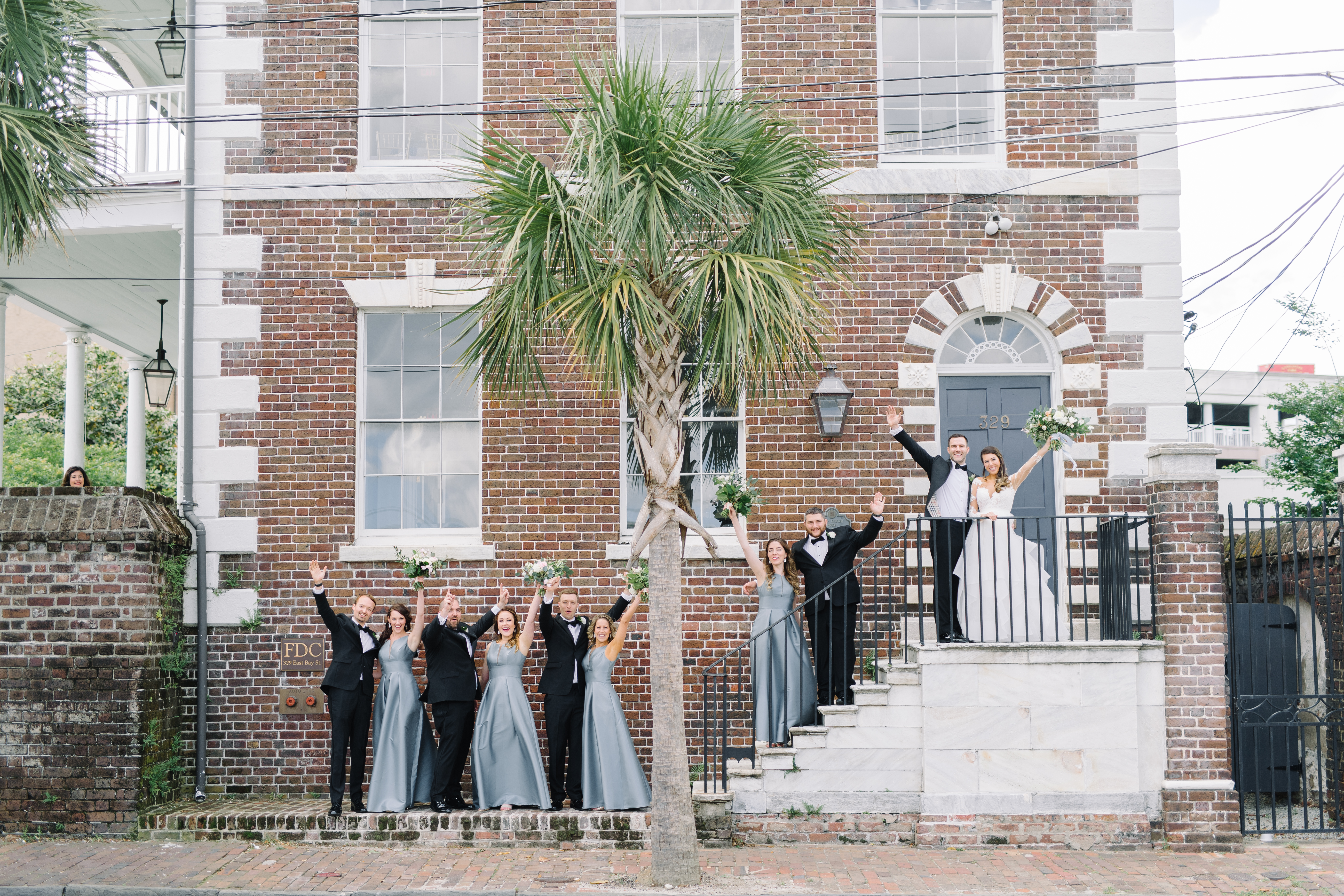 Bride and groom with their bridal party in front of the Gadsden House. Black tie wedding. Wedding gown with lace sleeves