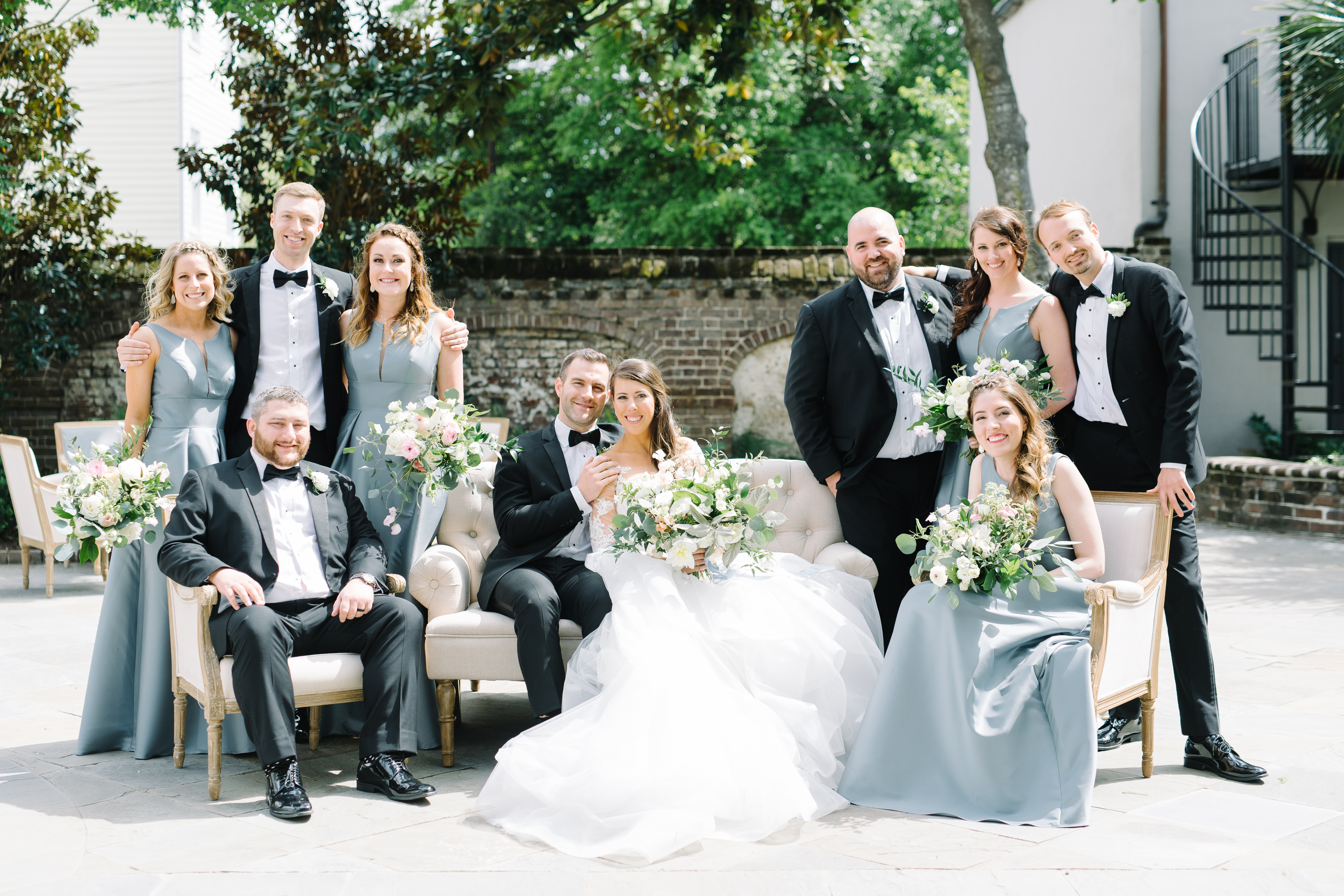 Bride and groom with their bridal party on the lounge furniture. Black tie wedding. Wedding gown with lace sleeves