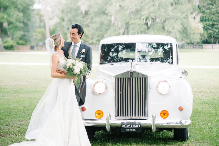 Nahila and Bernard in front of their vintage white Bentley at their Middleton Place wedding by Charleston wedding photographers Aaron and Jillian Photography_00108